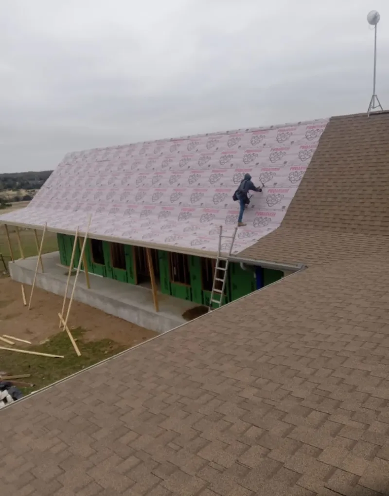 Worker preparing underlayment for a metal roof installation in Bedford